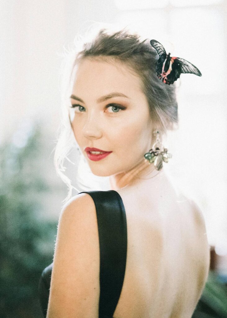Elegant bridal model with butterfly hair accessory and statement earrings for luxury weddings.
