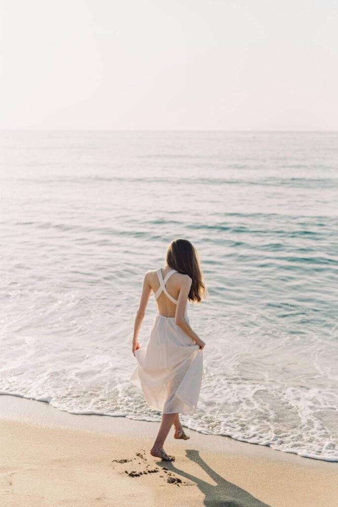 Elegant bride walking along the beach in a white wedding dress, seaside wedding venue with ocean view.