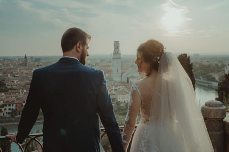 Elegant wedding couple overlooking historic cityscape at luxurious high-end venue at sunset.