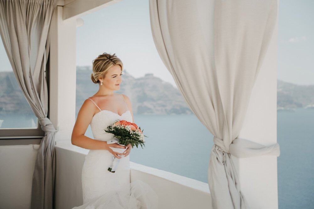 Elegant bride holding a bouquet overlooking the sea from a high-end luxury wedding venue.