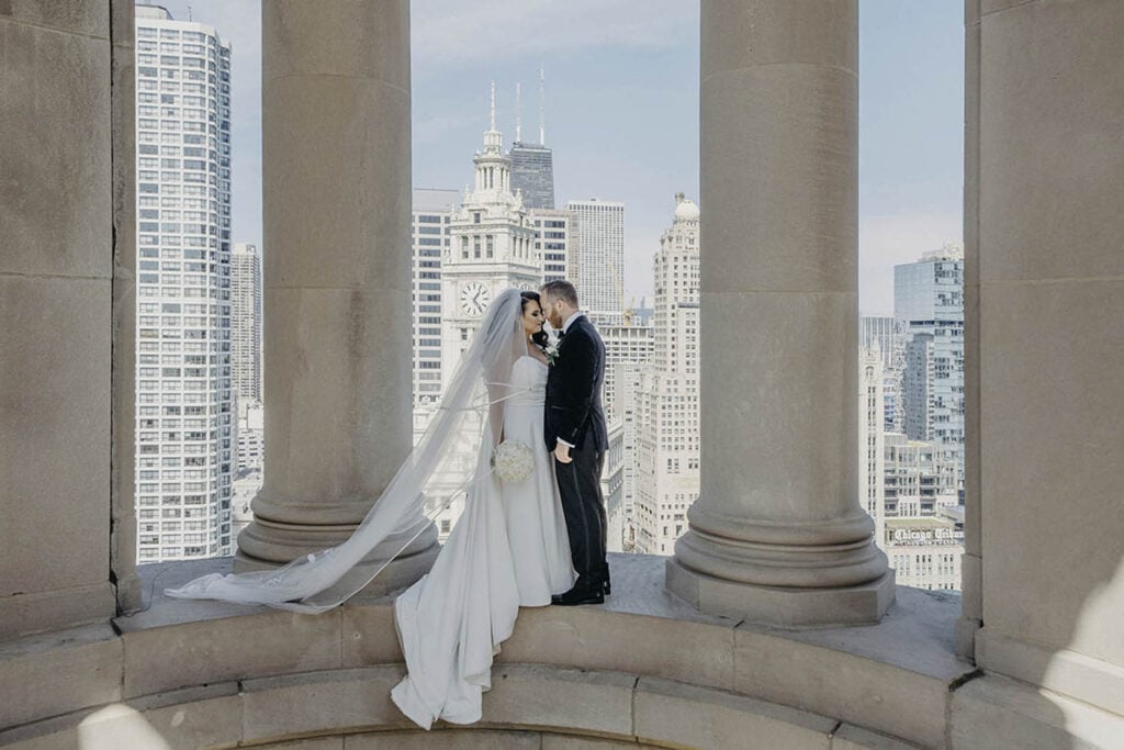 Elegant bride and groom on a rooftop balcony overlooking Chicago skyscrapers, perfect for luxury wedding photography.