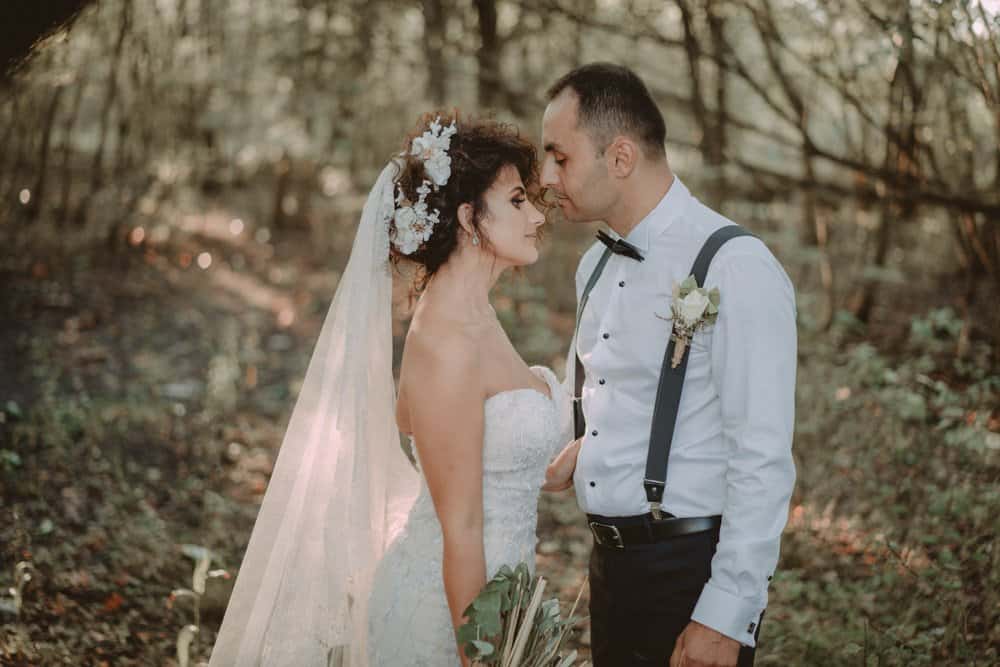 Elegant bride and groom in a romantic woodland wedding setting, showcasing luxury wedding attire and high-end design.