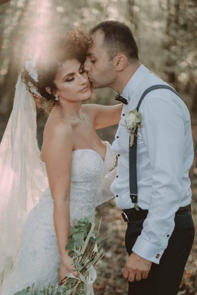 Elegant outdoor wedding with a romantic couple in a natural wooded setting, showcasing luxurious wedding beauty and intimate moments.