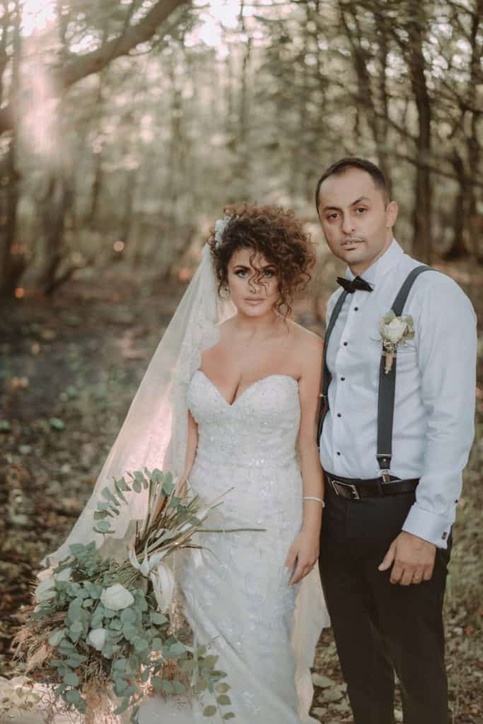 Elegant bride and groom in a forest setting, showcasing luxury wedding photography with natural light and high-end styling.
