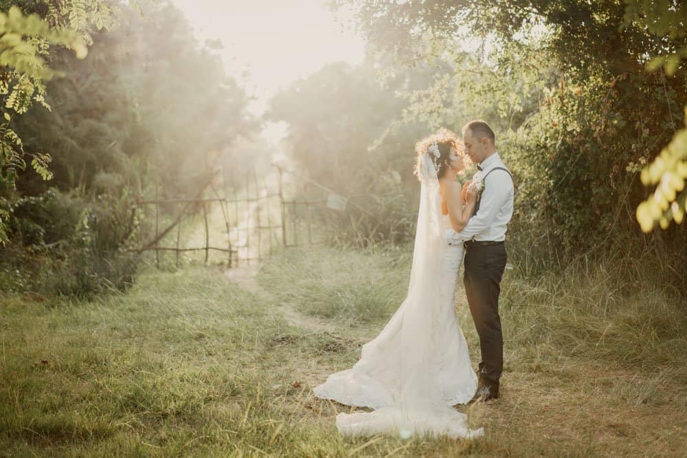 Elegant bride and groom sharing a romantic moment outdoors at sunset in a lush, private garden wedding venue.