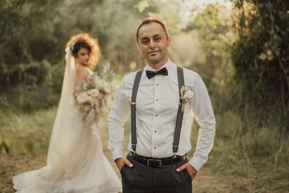 Elegant groom in classic tuxedo at luxurious outdoor wedding setting.