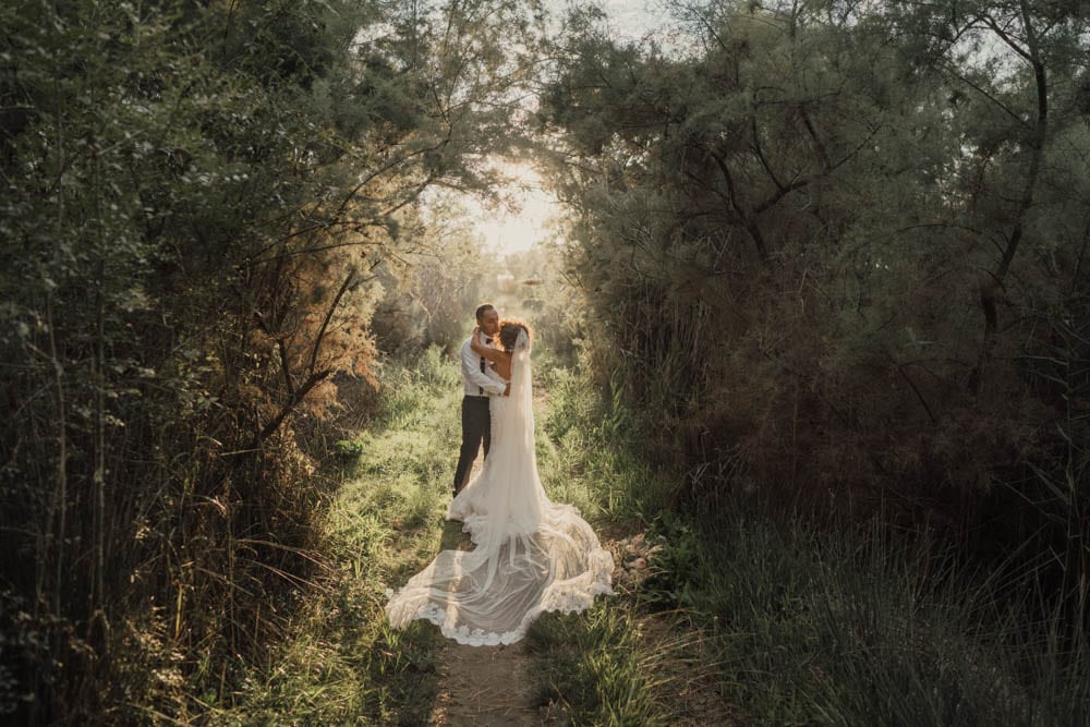Elegant wedding couple embracing in a lush forest setting during golden hour, capturing a romantic and dreamy moment.
