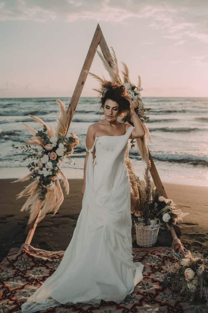 Elegant beach wedding dress in a romantic coastal scenery at sunset.