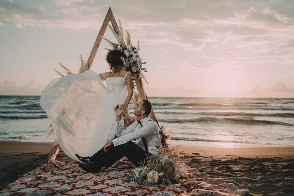 Elegant beach wedding with a couple at sunset on a luxurious sandy shore.