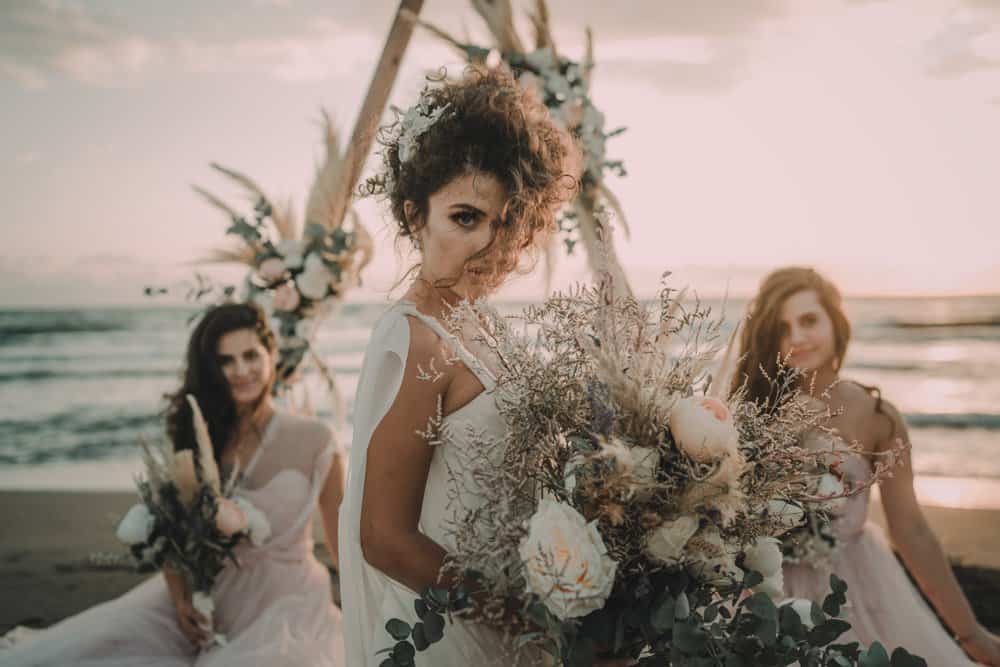 Eco-friendly boho bridal bouquet at sunset luxury beach wedding.