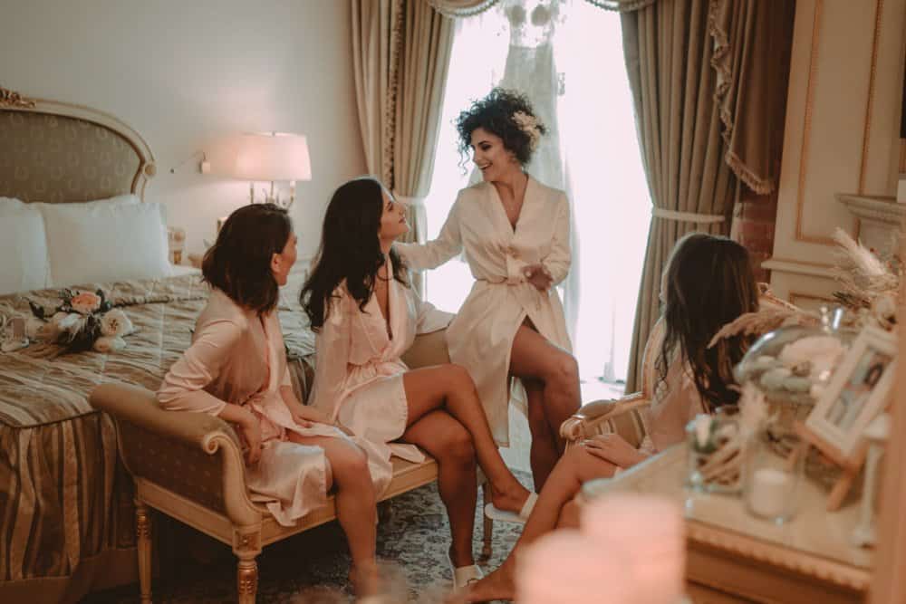 Bride and bridesmaids getting ready in elegant hotel room, luxury wedding preparation, high-end bridal suite, sophisticated bridal party, romantic wedding day ambiance.