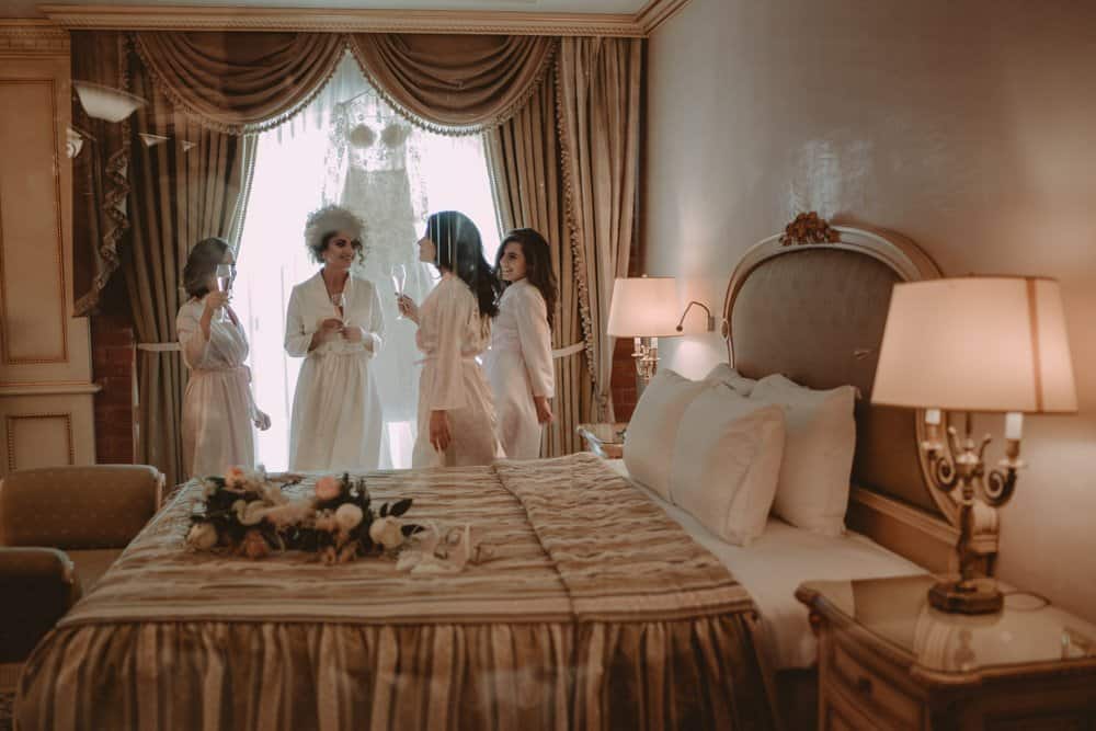 Elegant bridal party preparing in a luxurious vintage hotel room before a wedding ceremony.