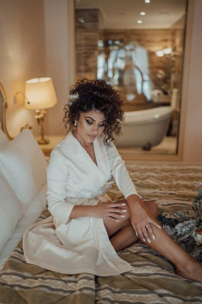 Elegant bride getting ready in a luxurious hotel room with warm lighting and sophisticated decor.