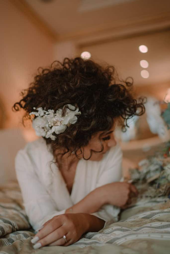 Luxury wedding bride with curly hair and floral hairpiece in a high-end venue.