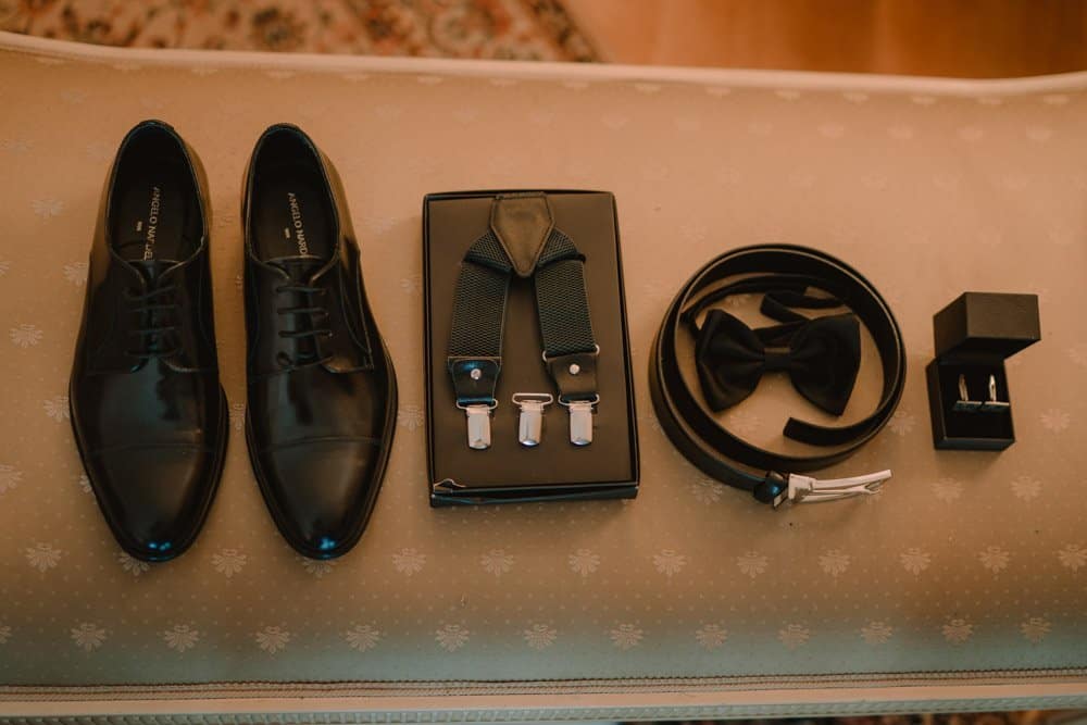 Elegant black men's dress shoes with matching accessories for a luxury wedding.