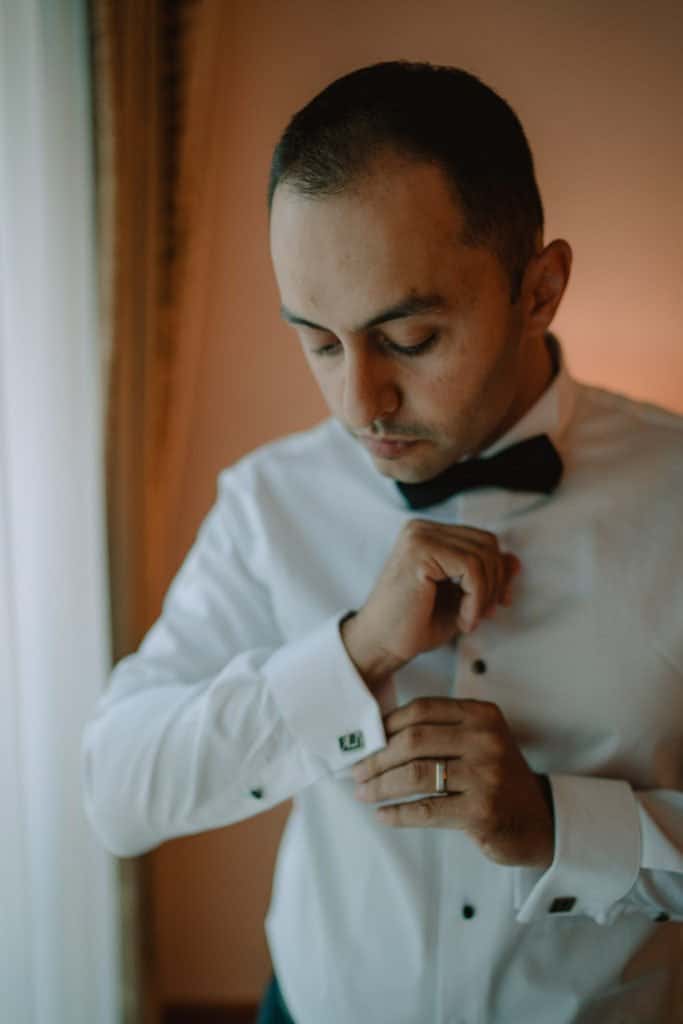 Elegant groom adjusting his cufflinks before a luxury wedding at a high-end venue.