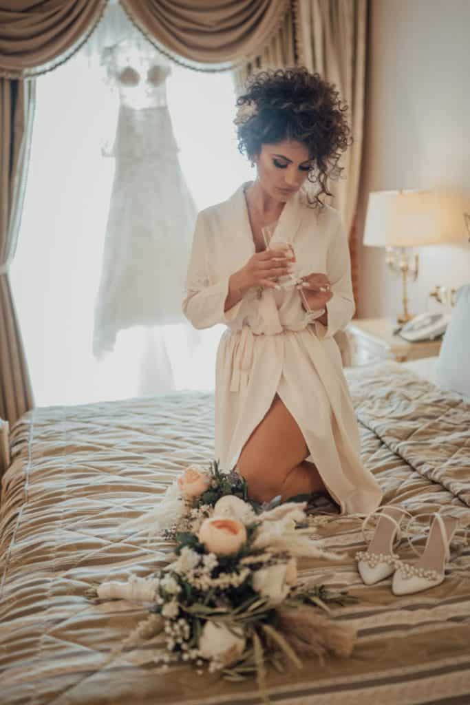 Elegant bride getting ready in a luxury hotel suite, soft natural light highlights her delicate bridal attire.