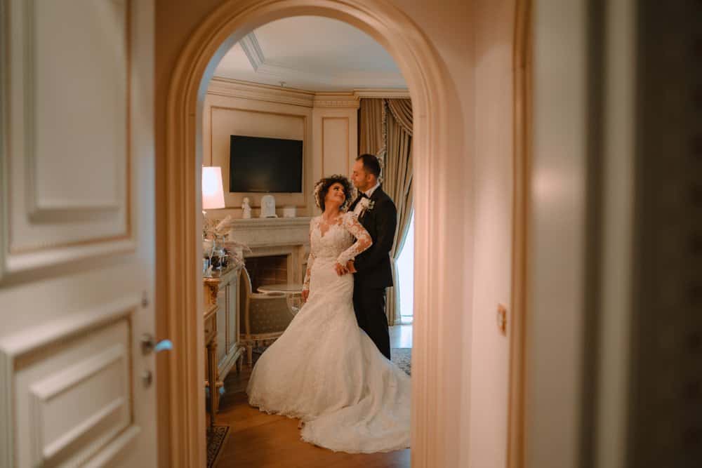 Elegant wedding couple in luxurious vintage-style suite with ornate woodwork and classic decor.
