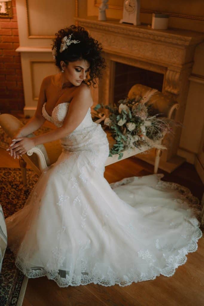 Bridal portrait in elegant wedding dress with floral details in cozy upscale room.