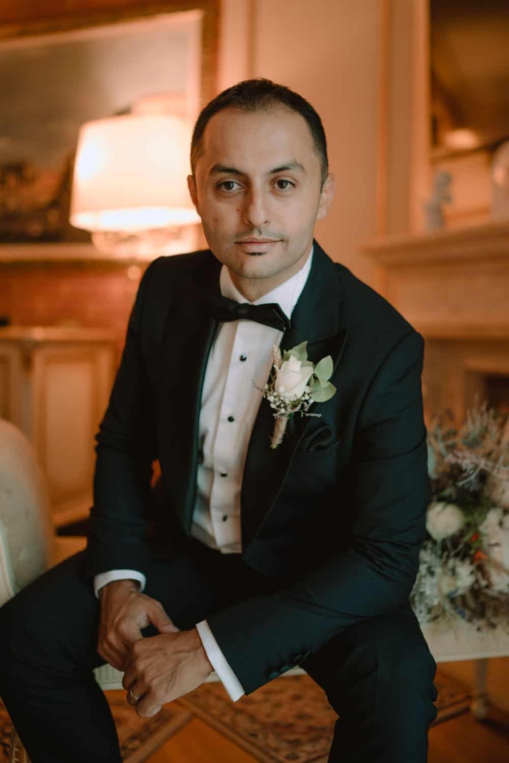 Elegant groom in classic tuxedo at luxury wedding venue.