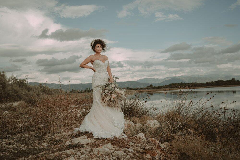 Elegant bride in a stunning wedding gown by a serene lakeside in nature, perfect for luxury wedding photography.