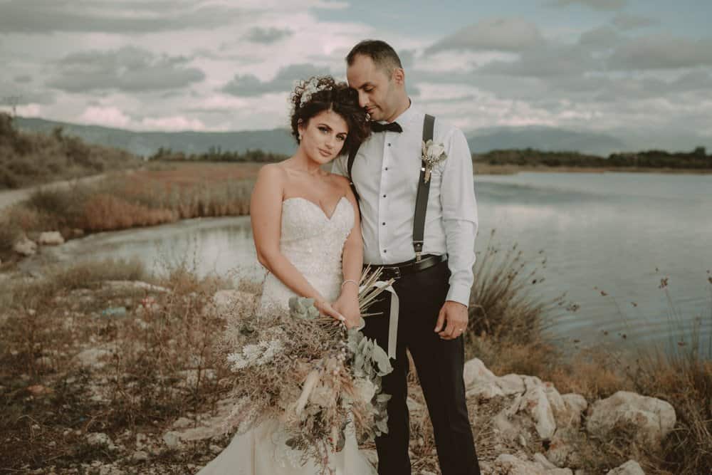 Elegant bride and groom in a lakeside setting, showcasing luxury wedding photography by Visi Studio.