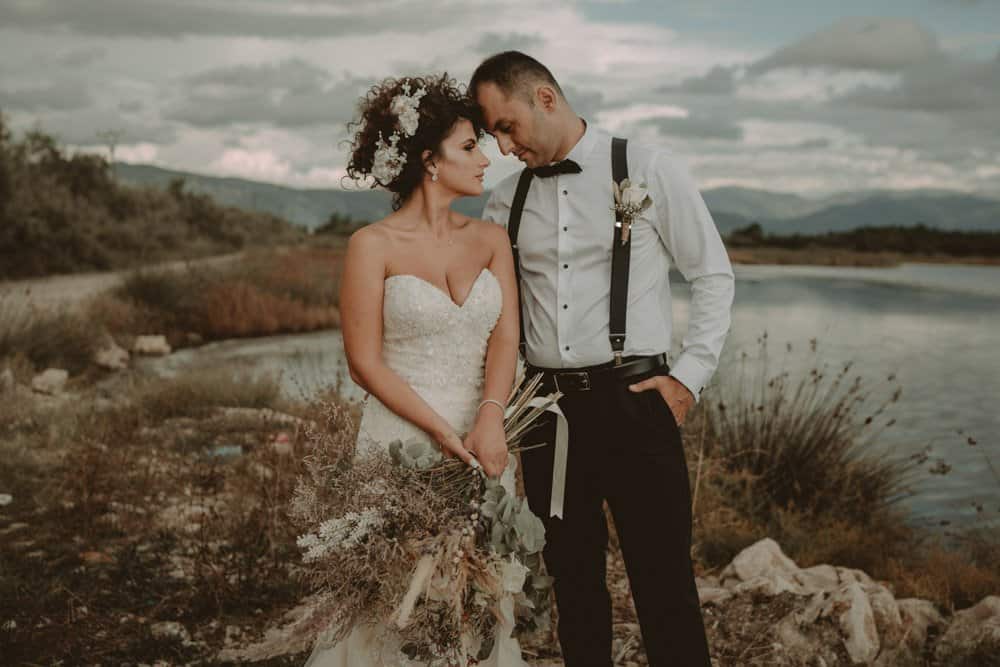 Elegant wedding couple by a serene lake at a luxurious outdoor venue, perfect for high-end destination weddings.