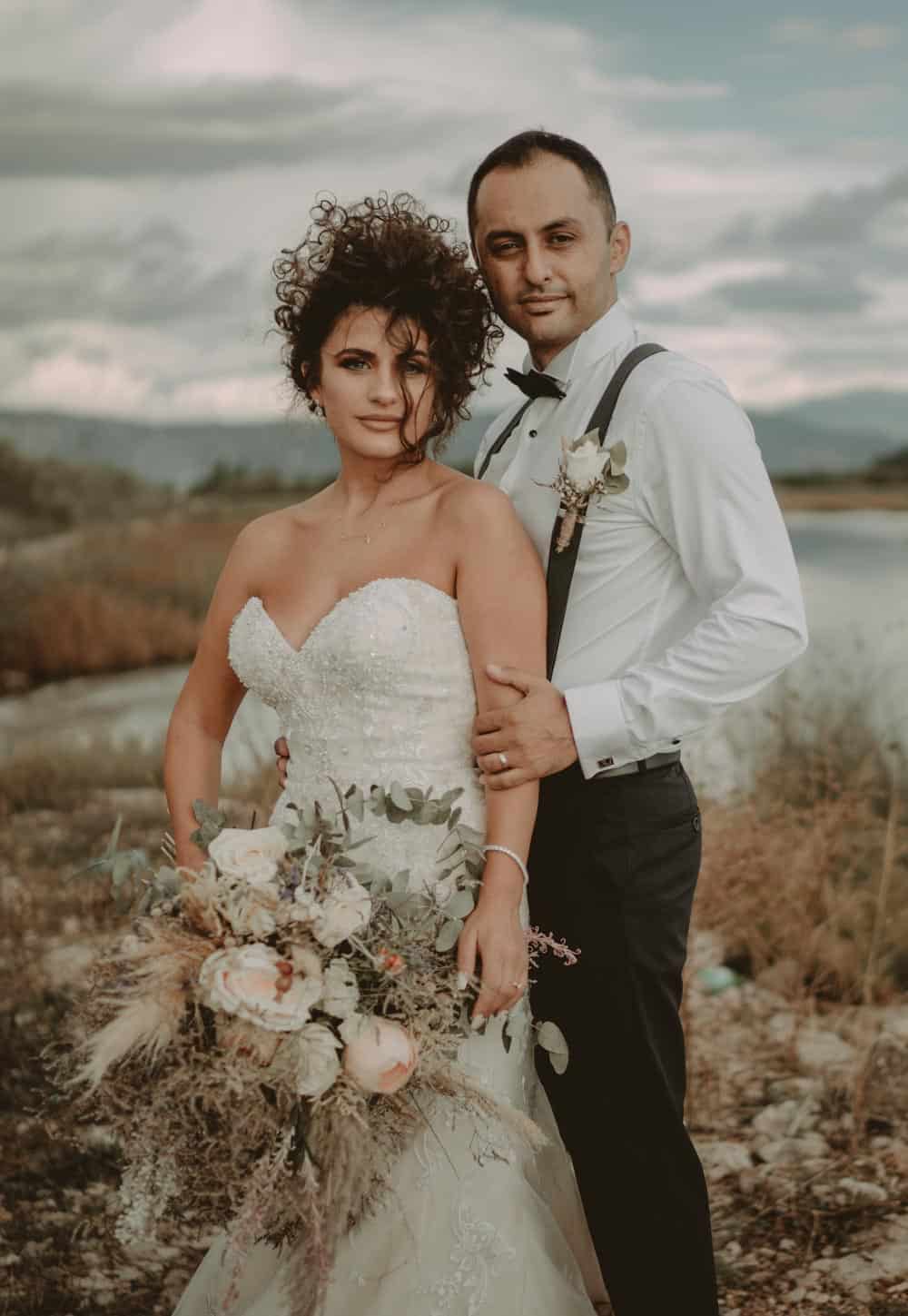 Elegant wedding couple in romantic outdoor setting at sunset, showcasing luxury wedding fashion and scenic high-end venue backdrop.