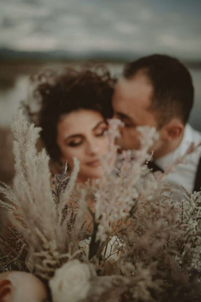 Elegant couple sharing an intimate moment amidst lush floral arrangements at a luxurious outdoor wedding venue.