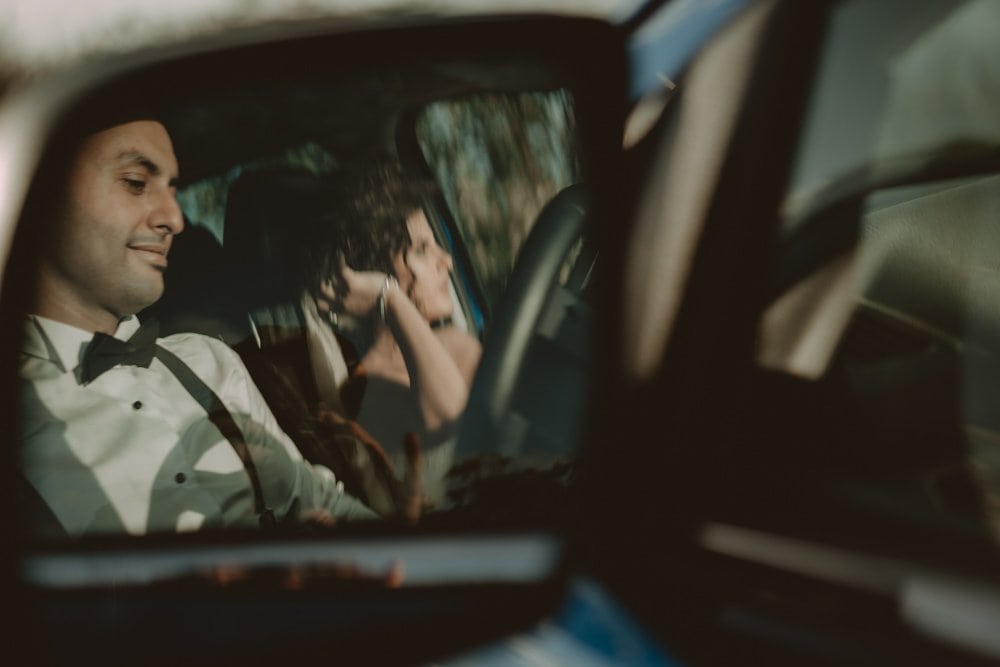 Elegant groom in a tuxedo sitting in a luxury car for a wedding celebration.
