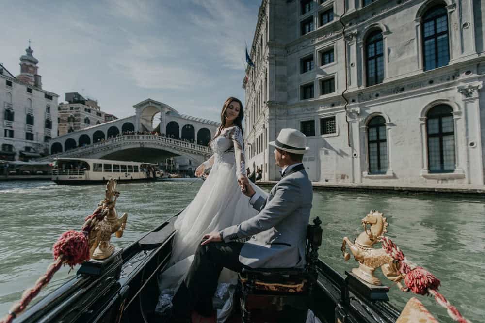 Elegant bride and groom on a romantic gondola ride in Venice, Italy, showcasing luxury wedding moments on the iconic waterways.
