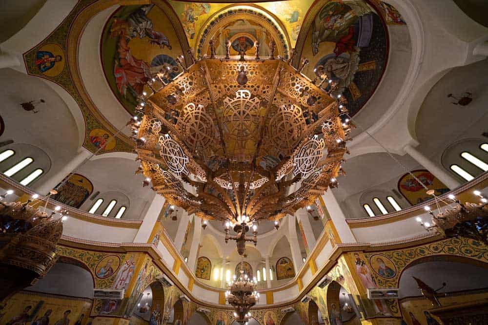 Opulent church interior with intricate wooden chandelier and religious murals, perfect for luxury wedding ceremonies.