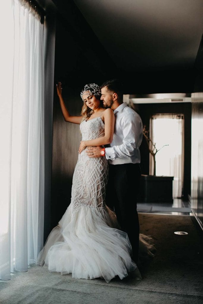 Elegant bride and groom in luxurious wedding attire in sophisticated modern venue.