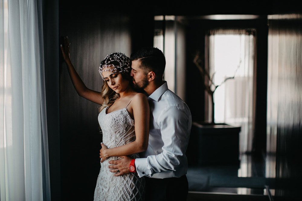 Elegant bride and groom embracing in a modern luxurious venue, capturing a romantic moment before their wedding.