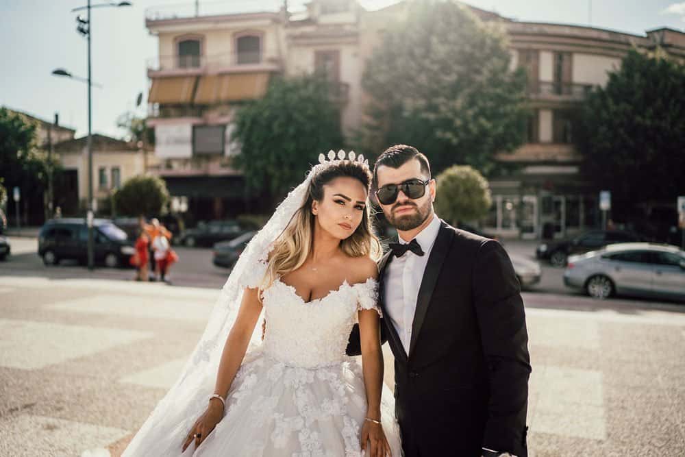 Elegant bride and groom outdoor portrait at luxury wedding venue, showcasing high-end fashion and stylish accessories.