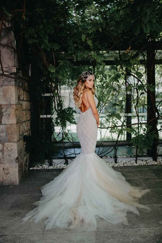 Elegant bridal gown with intricate lace details and dramatic train, perfect for luxury wedding venues.