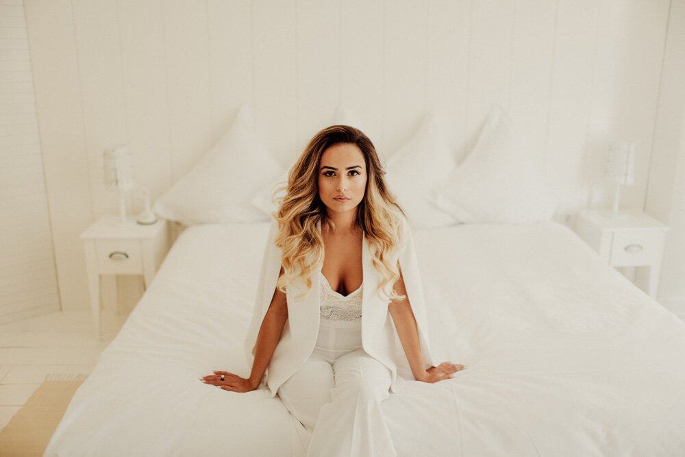Elegant bridal portrait in a luxurious white bedroom with high-end decor and sophisticated ambiance.