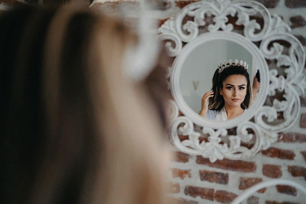 Elegant bride preparing for her wedding, adjusting her tiara in a luxurious high-end venue.
