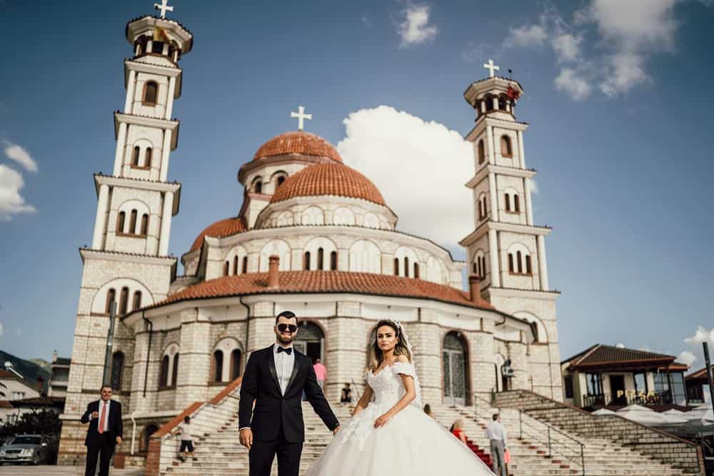 Elegant wedding couple in front of a stunning high-end church with luxurious architecture.