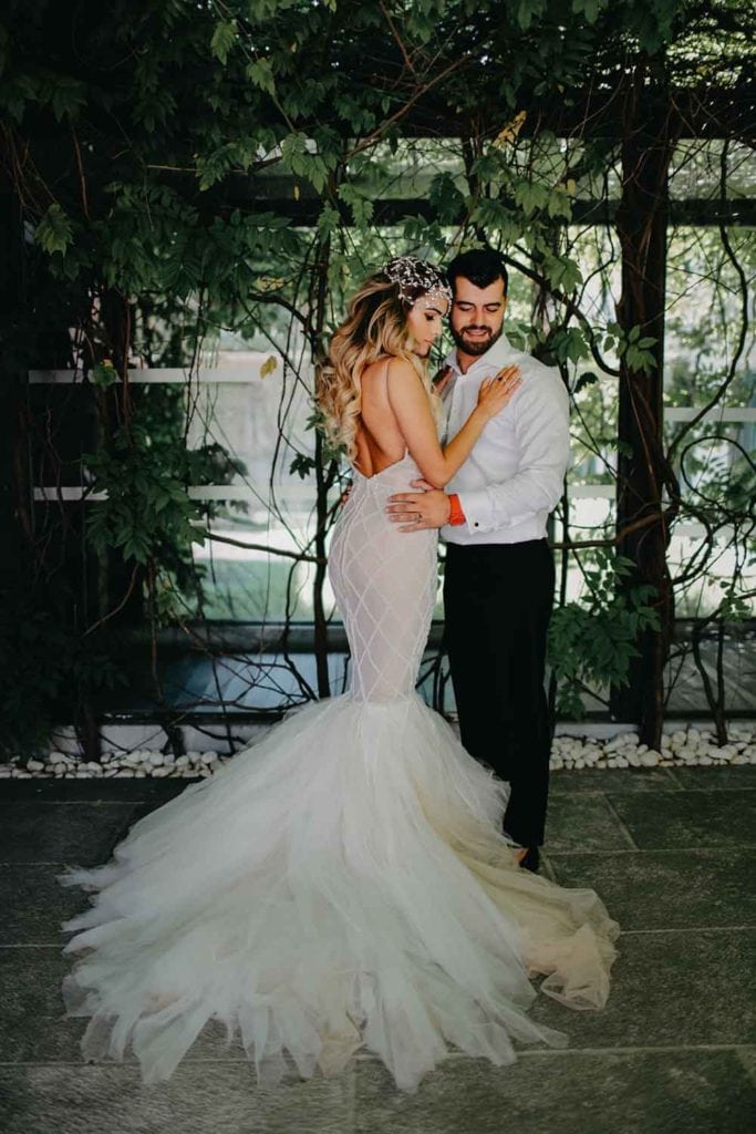 Elegant wedding couple embracing in lush garden setting, perfect for luxury wedding venues and high-end event decor.