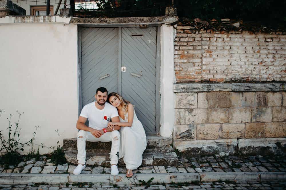 Luxury wedding couple sitting in front of a rustic door at high-end venue, romantic, elegant.