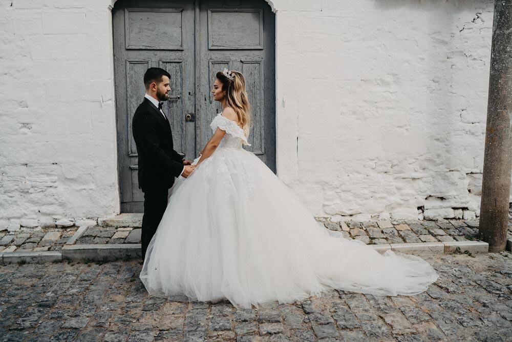 Luxurious wedding couple in elegant attire outside a stylish venue.