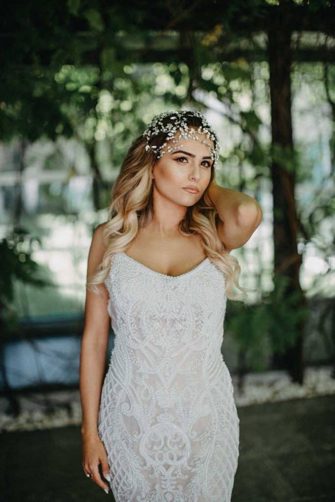 Elegant bride in intricate lace wedding gown with dramatic headpiece, perfect for luxury wedding events.