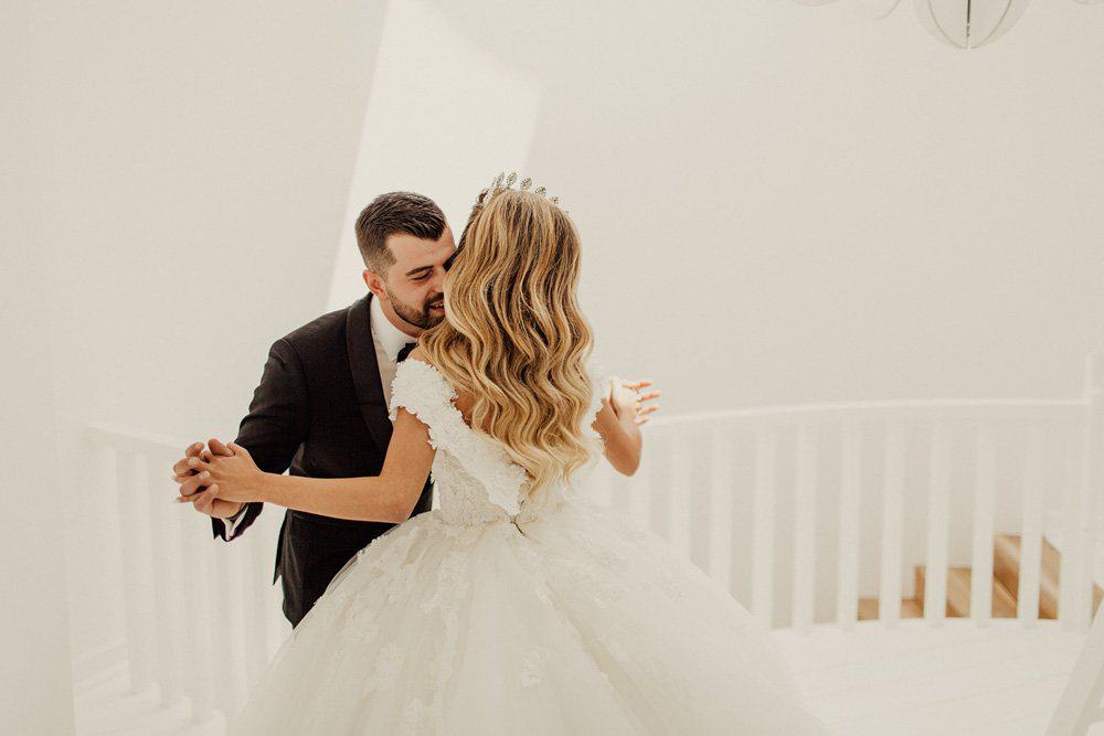 Elegant bride and groom sharing a first dance in a luxurious wedding venue with white minimalistic interior.