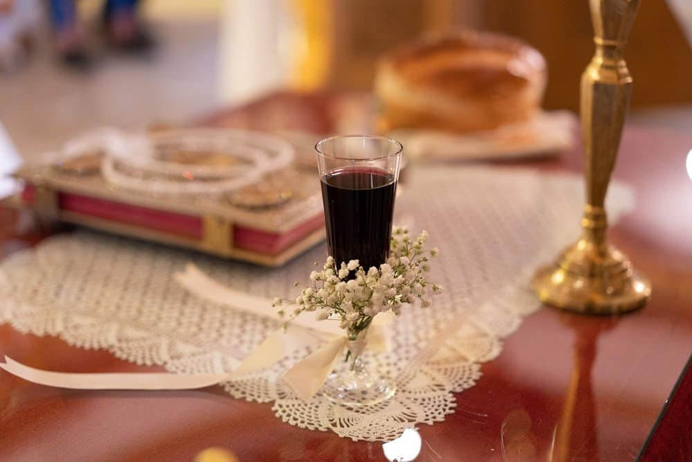 Vow renewal glass of red wine on lace doily with floral embellishment and gold accents at luxury wedding venue.