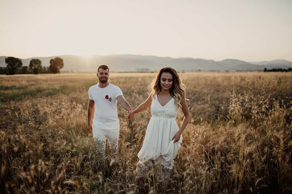 Golden hour couple walking through a wheat field in a romantic, scenic wedding photoshoot.