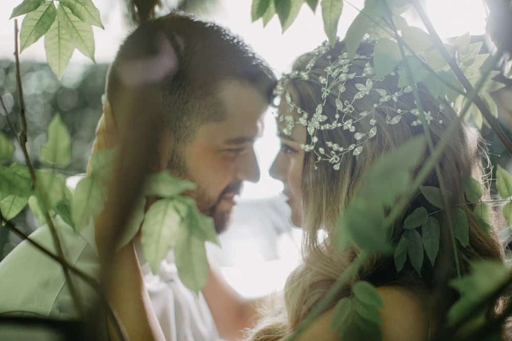 Intimate couple surrounded by greenery at a luxury wedding, love and elegance, high-end outdoor venue.