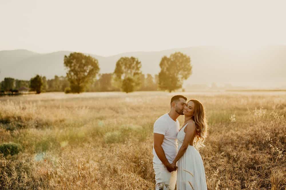 Luxury wedding couple in a scenic field during sunset.