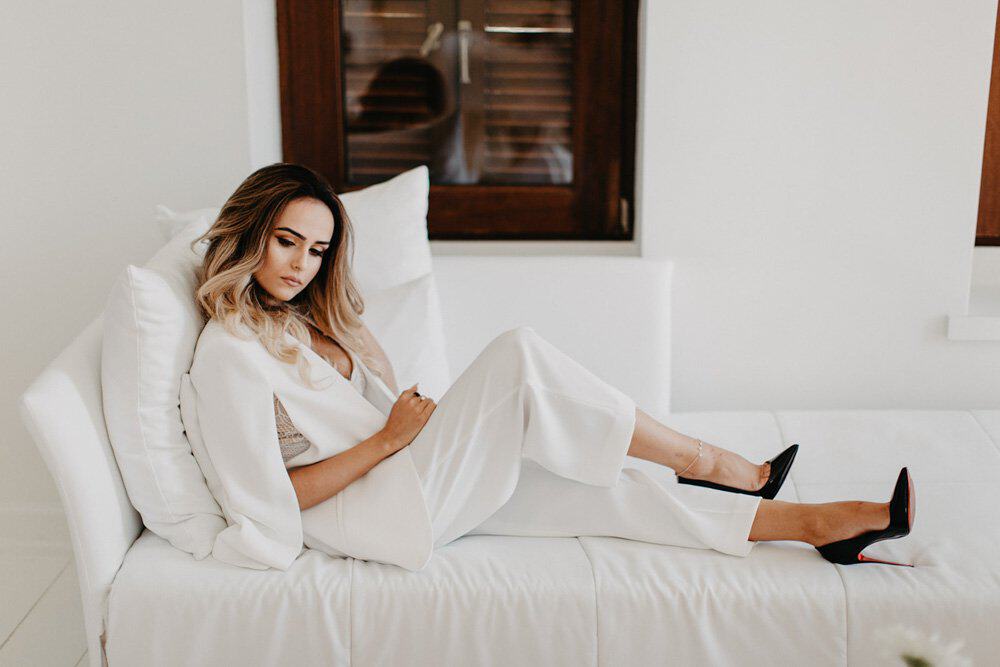 Luxurious bride relaxing on a white sofa in a high-end wedding venue.
