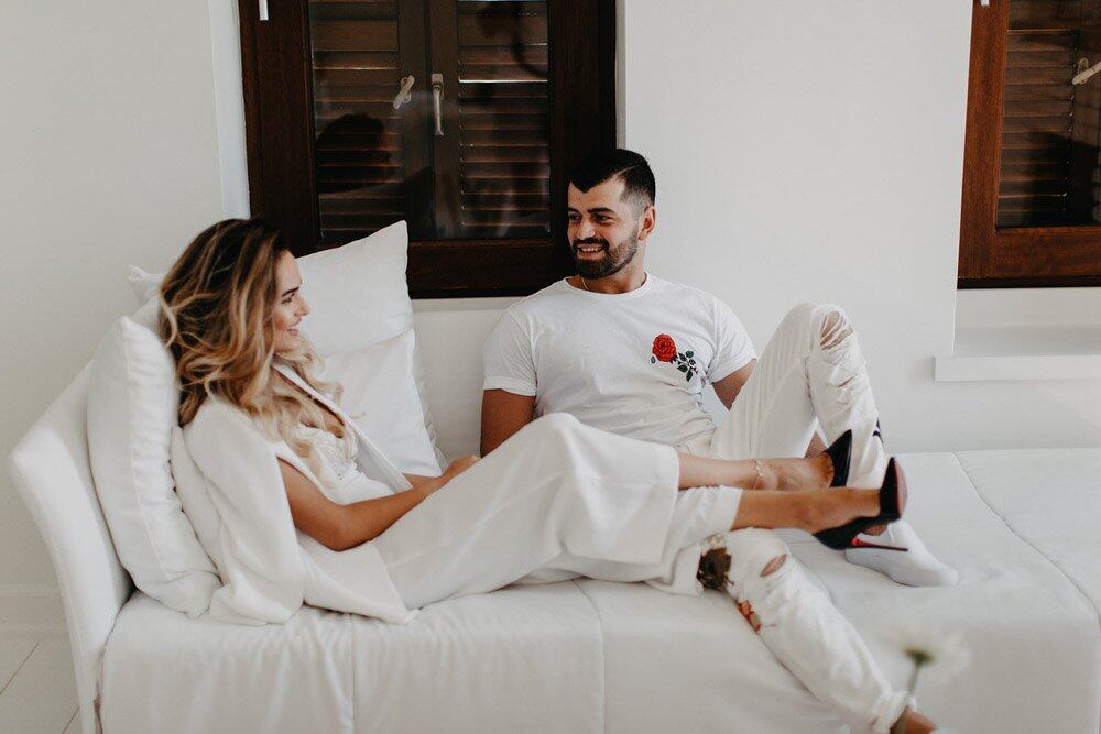 Elegant couple relaxing on a white luxurious couch, perfect for high-end wedding celebrations.